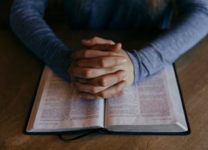 Henkilö rukoilemassa ja tutkimassa pyhiä kirjoituksia