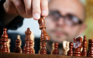 Silmälasipäinen mies pelaa shakkia, jossa on tärkeää tehdä valintoja