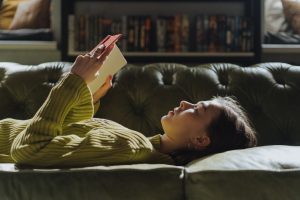 Tyttö lukee sohvalla. Kuva esittää, että lukemalla voi oppia itse.